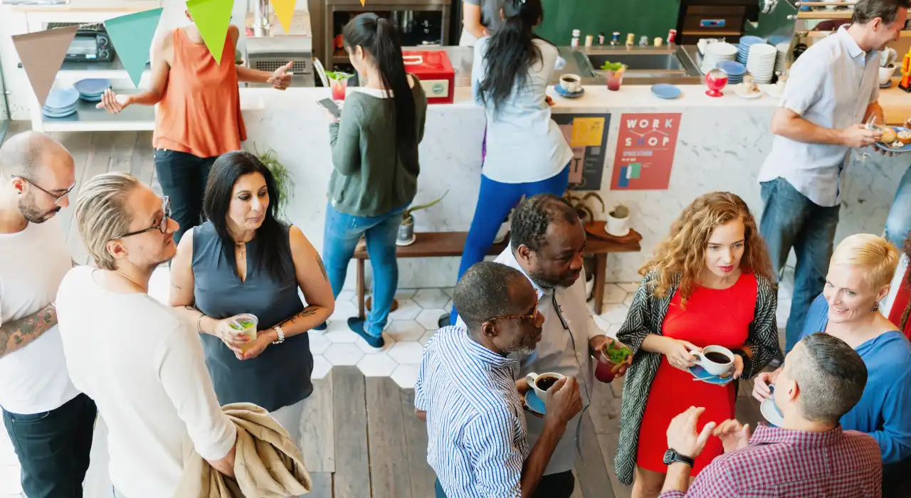 人們在競選辦事處的輕鬆活動中手持飲品交談。