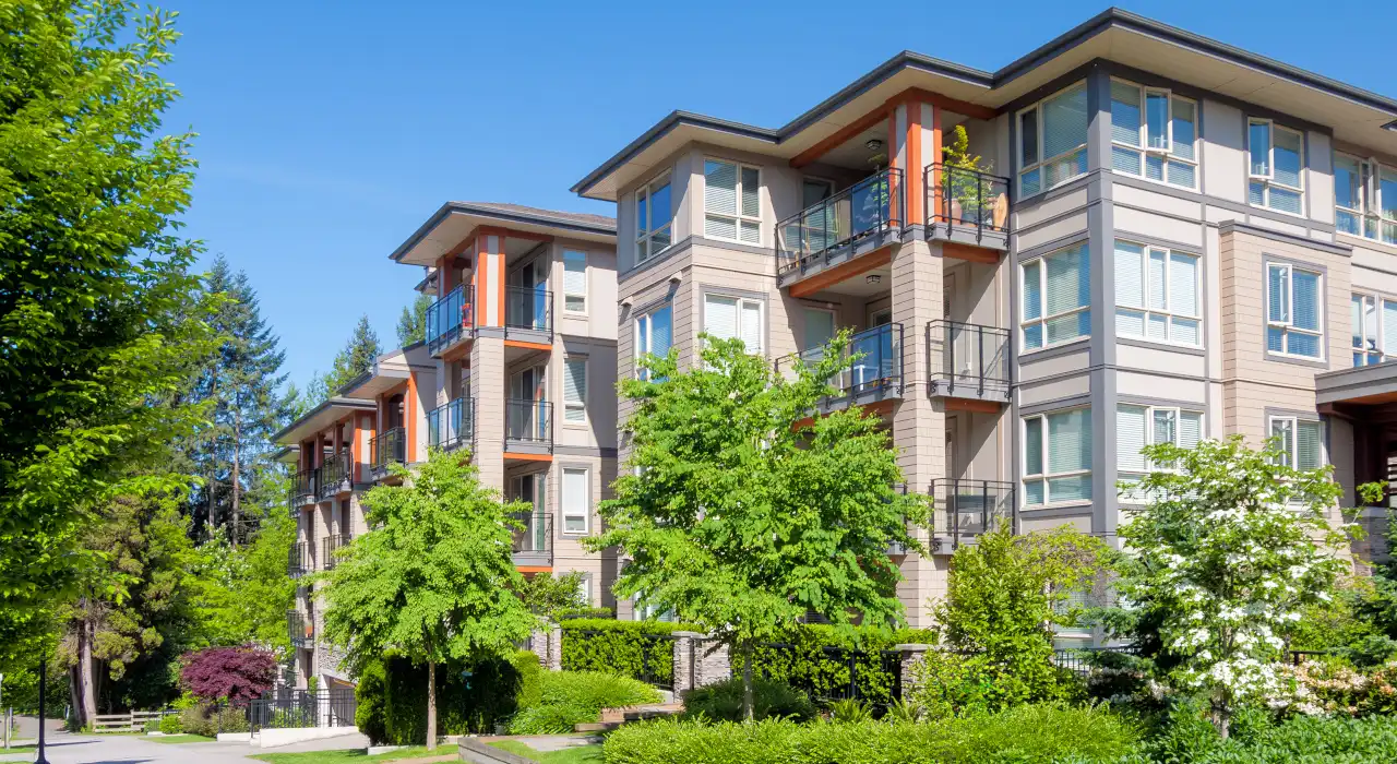 ਮੌਡਰਨ ਘੱਟ ਮੰਜ਼ਿਲਾਂ ਵਾਲੀਆਂ ਇਮਾਰਤਾਂ, ਬਾਲਕਨੀ ਵਾਲੀਆਂ, ਹਰੇ-ਭਰੇ ਦ੍ਰਿਸ਼ ਨਾਲ ਘਿਰੀਆਂ ਹੋਈਆਂ, ਧੁੱਪ ਵਾਲੇ ਦਿਨ ਵਿੱਚ।