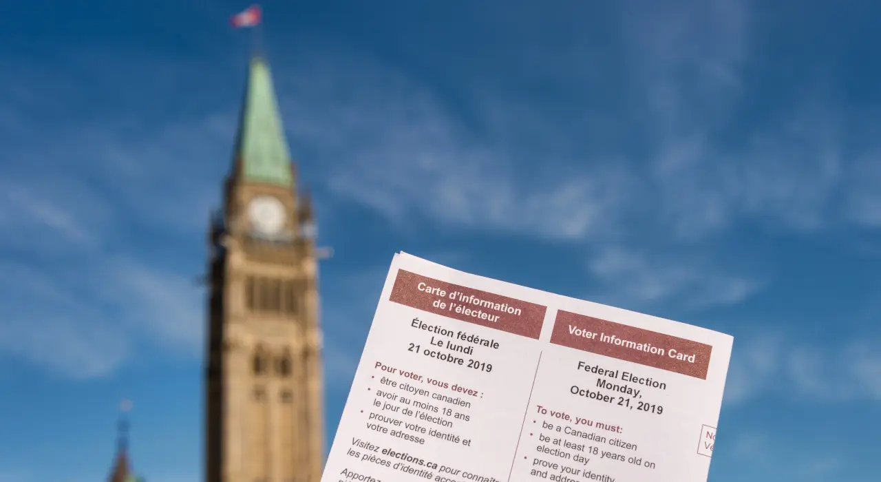 一張選民資訊卡在加拿大國會和平塔前舉起。