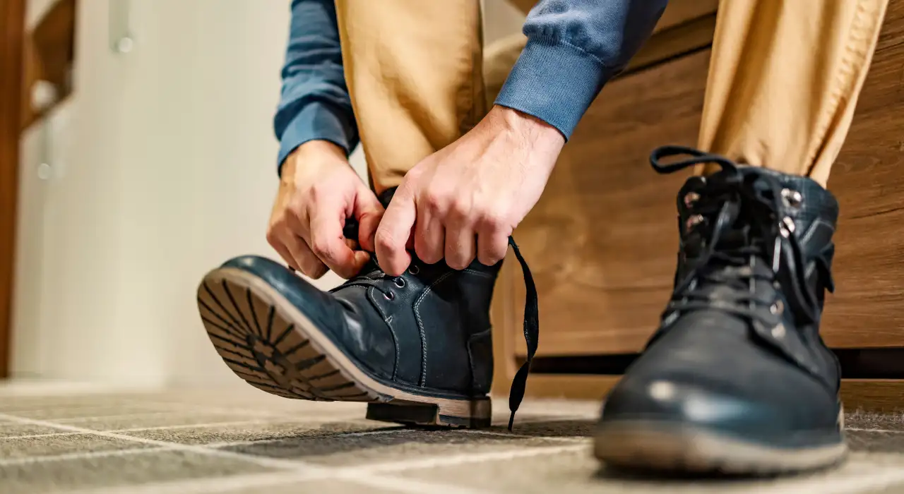 特寫一個人正在繫黑色結實靴子的鞋帶，準備外出。