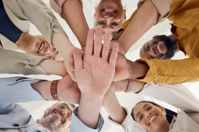 Group of people stacking their hands together in a gesture of teamwork and unity